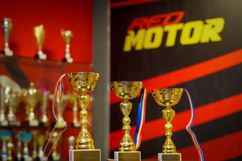 Cupe aurii cu panglică tricoloră în fața logoului Red Motor