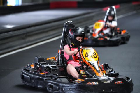 Copil cu cască și cagulă la volanul unui kart pe circuitul indoor Red Motor